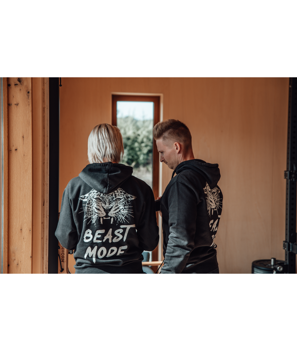 Zwei Personen in Kapuzenpullovern mit der Aufschrift BEAST MODE stehen in einem Haus und blicken von der Kamera weg.