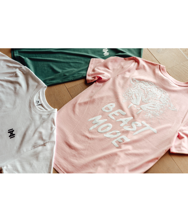 Drei T-Shirts liegen aus, eines rosa mit dem Text BEAST MODE, eines weiß und eines grün, alle mit einem kleinen Logo.